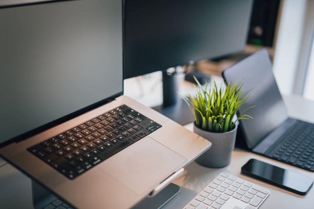 The Art of Drawing Readers In: Your attractive post title goes here A sleek office workspace featuring a laptop, smartphone, keyboard, and potted plant for productivity.
